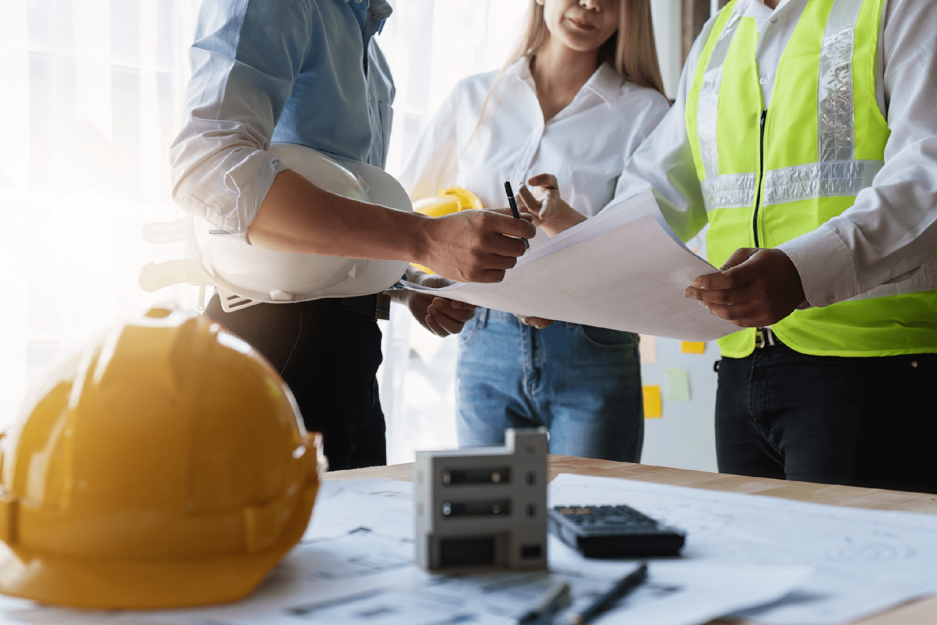 Team of engineers and architects working with blueprints at construction site.